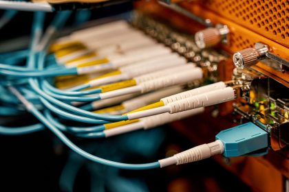 Equipamento de conexão óptica visto de cima, com diversos cabos e conectores dispostos em uma estrutura metálica