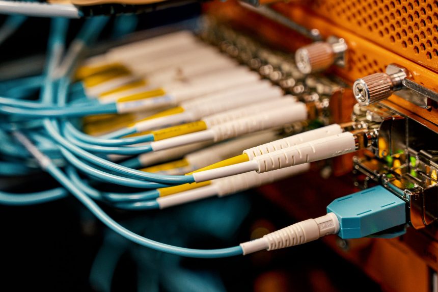 Equipamento de conexão óptica visto de cima, com diversos cabos e conectores dispostos em uma estrutura metálica