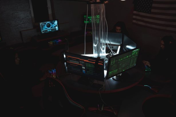 Equipe de profissionais monitora dados e sistemas de cibersegurança em uma sala com vários computadores.