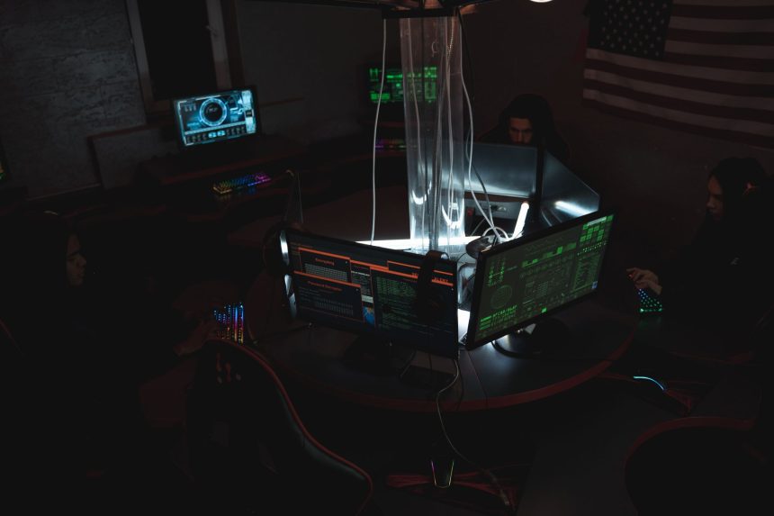 Equipe de profissionais monitora dados e sistemas de cibersegurança em uma sala com vários computadores.